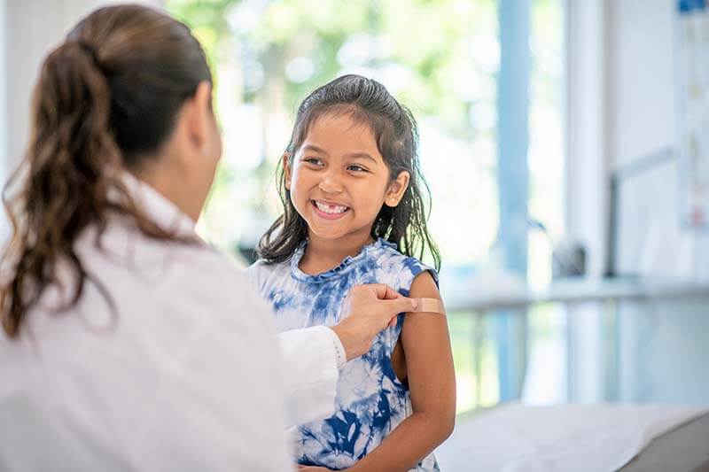 pediatrician putting bandaid on little girl